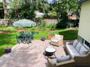 Une terrasse avec une table et des chaises, un canapé en osier et un parasol à rayures.