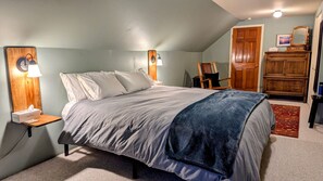 Une chambre à coucher avec un lit, des tables de chevet, une commode et une porte.