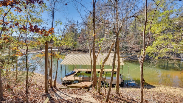 A cabin with a dock extending into a lake, surrounded by trees and a wooden deck. - Waterfront Lake Hartwell Home w/ Dock & Fire Pit (Hartwell)