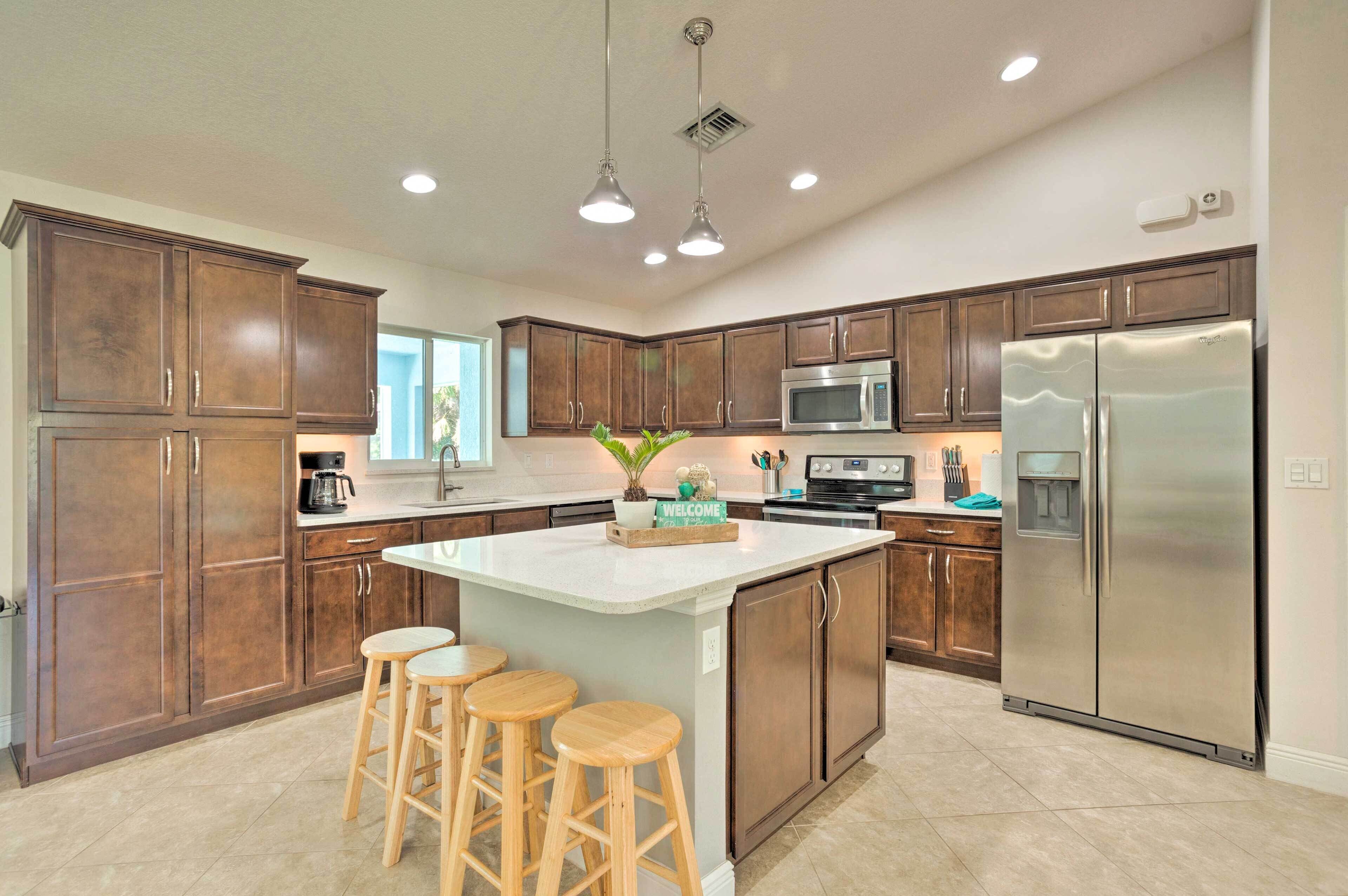 A modern kitchen with dark wooden cabinets, a stainless steel refrigerator, a microwave, and a large island with stools.