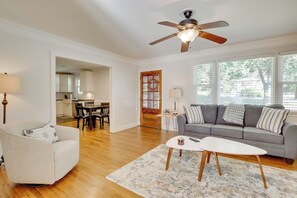 A living room with a gray sofa, a white armchair, a coffee table, and a ceiling fan. - Contemporary Athens Home < 2 Miles to UGA! (Athens)