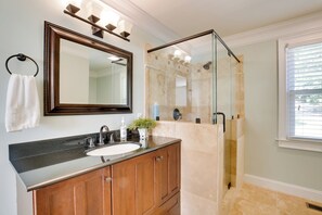 A bathroom with a wooden vanity, a large mirror, a glass-enclosed shower, and a window with blinds. - Contemporary Athens Home < 2 Miles to UGA! (Athens)
