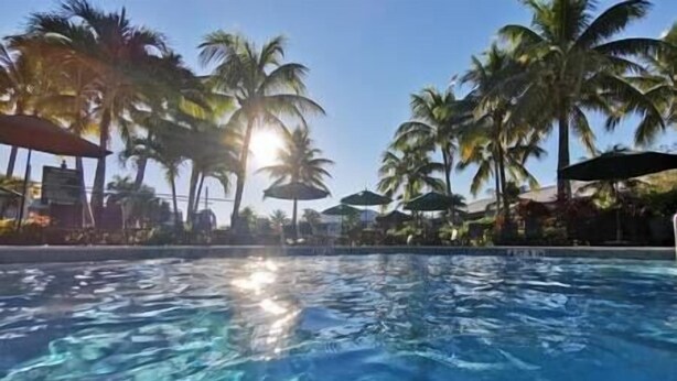 A swimming pool with clear water, surrounded by palm trees and umbrellas. - Greenlinks Luxury Condo, 3BD, ground floor, golf, pool (Naples)