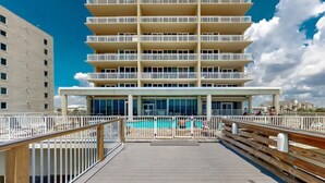 Un hotel de varios pisos con una zona de piscina accesible a través de una terraza de madera.