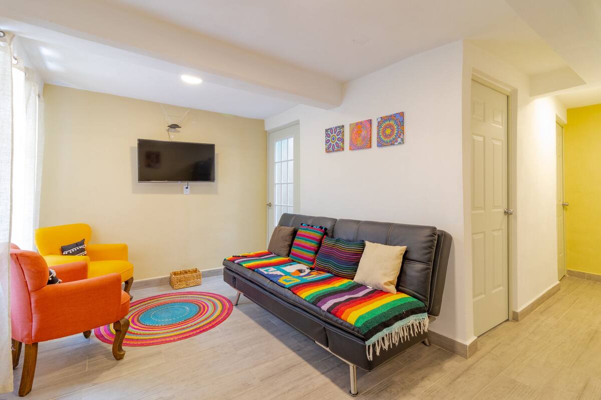 A living room with a sofa, armchairs, a flat-screen TV, and decorative pillows.