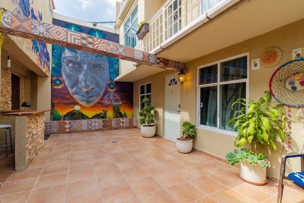 A courtyard with a mural, potted plants, and a bar area.