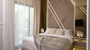 A modern bedroom with a large bed, a bedside table, a mirror, and a unique ceiling light fixture. - SLV Smart Living Villa (دبيdubai)
