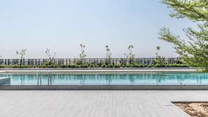 A swimming pool with a clear view of the sky and a row of trees in the background. - SLV Smart Living Villa (دبيdubai)