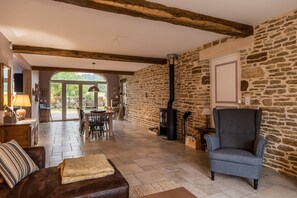 A spacious living area with a stone wall, a fireplace, and a comfortable seating area. - Old farmhouse, renovated in 2021, 4-star, charming, relaxation in the heart of nature (Lizine)