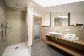 A modern bathroom with a glass-enclosed shower, a wooden vanity with a sink, and a mirror.