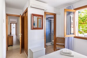 Ein Hotelzimmer mit einem Bett, einem Holzstuhl, einem kleinen Tisch, einem Spiegel und einer Dusche.