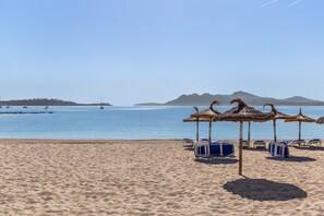 Een strand met rieten parasols en ligstoelen.