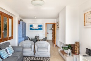 Un soggiorno con un divano, due poltrone, un tavolo da pranzo con sedie, un mobile azzurro e un quadro appeso al muro.