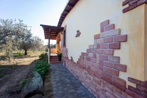 A pathway leading to a building with a brick wall and a pergola. - Pet-friendly Holiday Apartment "A contatto con la natura - Orosei" with Garden, Terrace & Wi-Fi (Orosei)