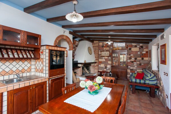 A kitchen with a stone wall, wooden cabinets, and a dining table with a vase of flowers.
