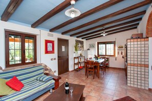 A room with a sofa, dining table, and kitchen area.