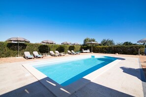 A swimming pool with lounge chairs and umbrellas, surrounded by a hedge and trees. - Villa 'Oliva AL' with Nature Views, Pool, Garden, Terrace, Wi-Fi & AC (Moncarapacho)