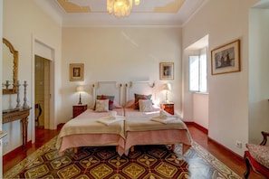 A hotel room with two beds, a chandelier, a mirror, and a patterned rug. - Villa 'Oliva AL' with Nature Views, Pool, Garden, Terrace, Wi-Fi & AC (Moncarapacho)