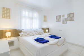 Une chambre d’hôtel avec un lit, des tables de chevet, une lampe et des œuvres d’art murales.
