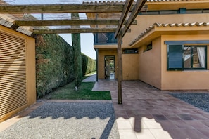 A modern house with a covered patio, a well-maintained garden, and a clear pathway leading to the entrance.