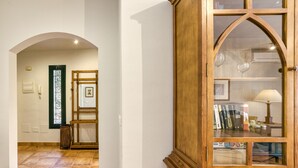 A hallway with a wooden cabinet, a framed picture, and a tiled floor. - Family villa in Torremirona Resort (Navata)