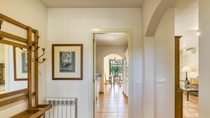 A hallway with a radiator, framed artwork, and a wooden bench. - Family villa in Torremirona Resort (Navata)