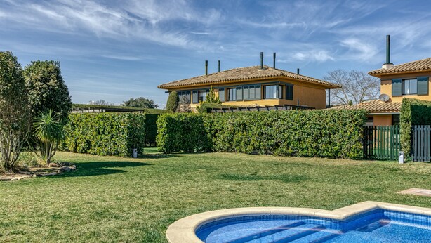 A residential property with a swimming pool, a well-maintained lawn, and a large house with a tiled roof. - Family villa in Torremirona Resort (Navata)