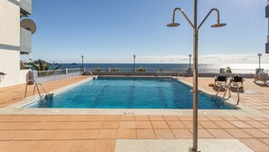 A rooftop pool with a clear view of the ocean, a metal pool ladder, and a metal pole with lights. - Apartment with Sea View, Balcony, and Air Conditioning (Almunecar)
