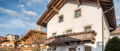 A multi-story building with a balcony, wooden beams, and a stone foundation.