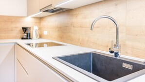 Une cuisine moderne dotée d’un évier en acier inoxydable, de meubles en bois et d’une hotte intégrée.