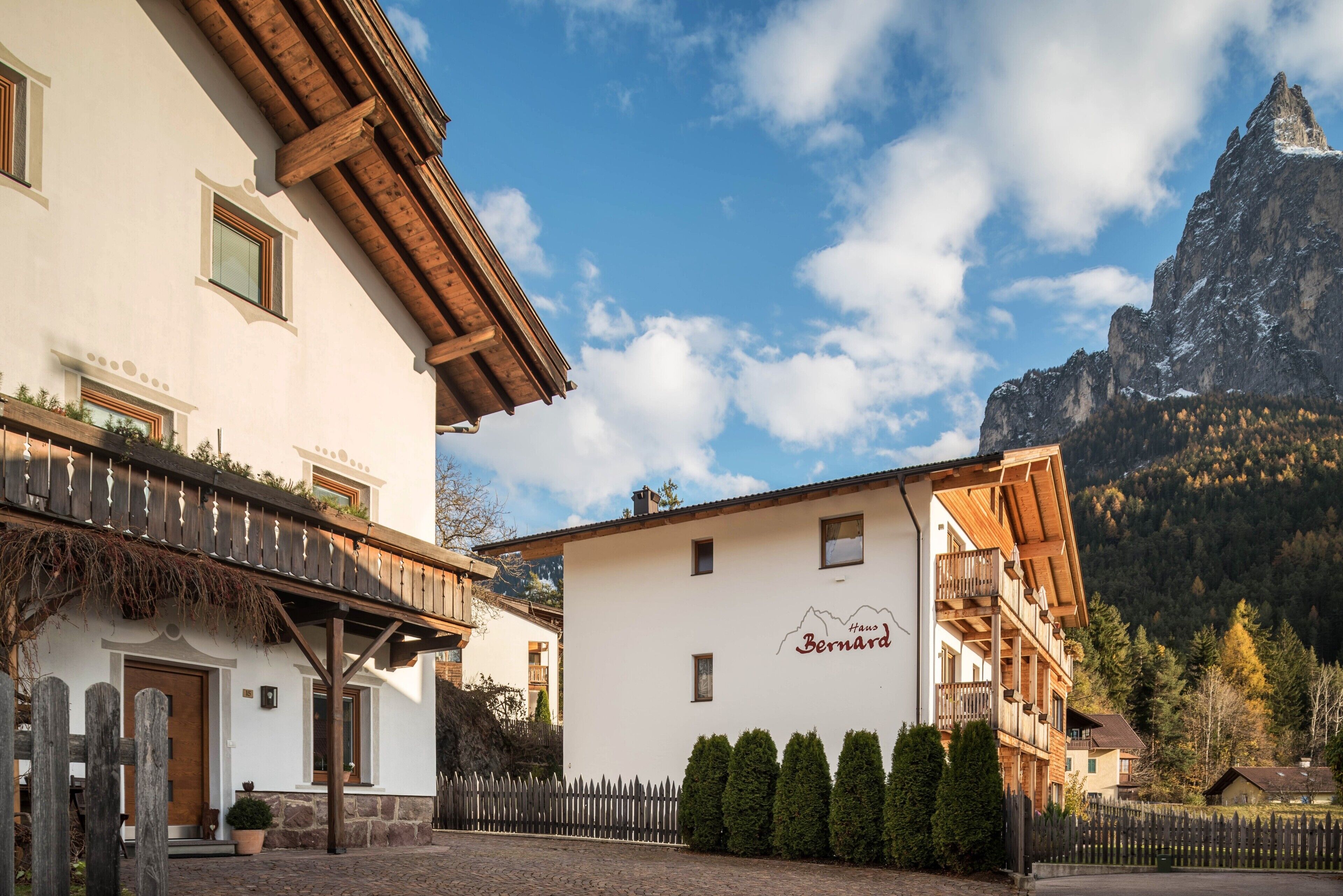 Tipico chalet con balcone in legno, vista sulle montagne e insegna con scritto 'Hugo Bernard'.