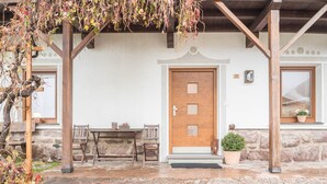 Un bâtiment en pierre avec une porte en bois, un banc, une table et une plante en pot.