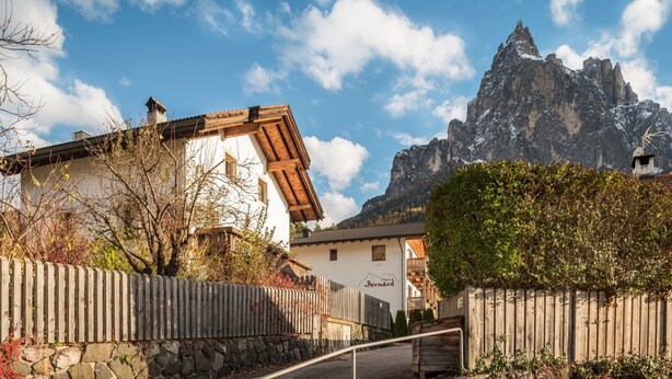 Un village de montagne aux maisons traditionnelles en bois, aux murs de pierre et dominé par un sommet montagneux imposant en arrière-plan.