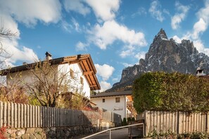 Een bergdorps gelegenheid met traditionele houten huizen, stenen muren en een markante bergtop op de achtergrond.