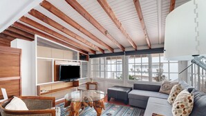 Un salón amplio con un televisor grande, asientos cómodos y vistas a través de amplias ventanas.