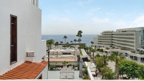 Un hotel con terraza que ofrece vistas al mar, palmeras y al océano.