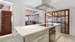 Cocina moderna con una isla grande, horno empotrado y vistas al patio exterior.