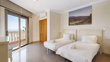 A hotel room with two beds, a balcony, and a painting of a landscape.