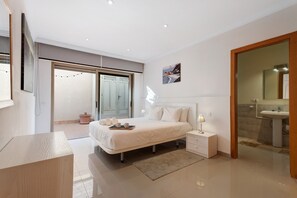 Ein modernes Schlafzimmer mit Bett, Nachttisch und einem Badezimmer mit Waschbecken und Spiegel.