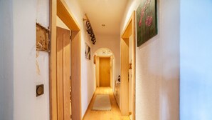 A hallway with wooden doors, a rug, and a painting on the wall. - Hoferhof Apartement 'Bergzauber' with Mountain View, Garden & Wi-Fi (Schenna)
