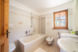 A bathroom with a bathtub, a bidet, and a sink.