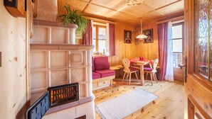 Un interior de madera con chimenea, un sofá, una mesa de comedor con sillas y una planta en maceta.
