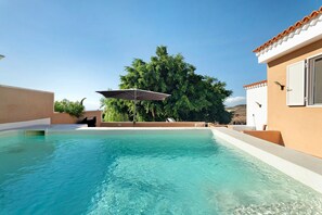 A swimming pool with a clear blue water, surrounded by a building with a tiled roof and a tree. - Rural Country House "Finca Los Corcos" with 2 Pools, Garden, Mountain & Sea View (guia de Isora)