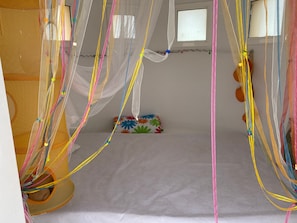 Ein Zimmer mit einem Bett, einem Fenster und einem Hängenetui.