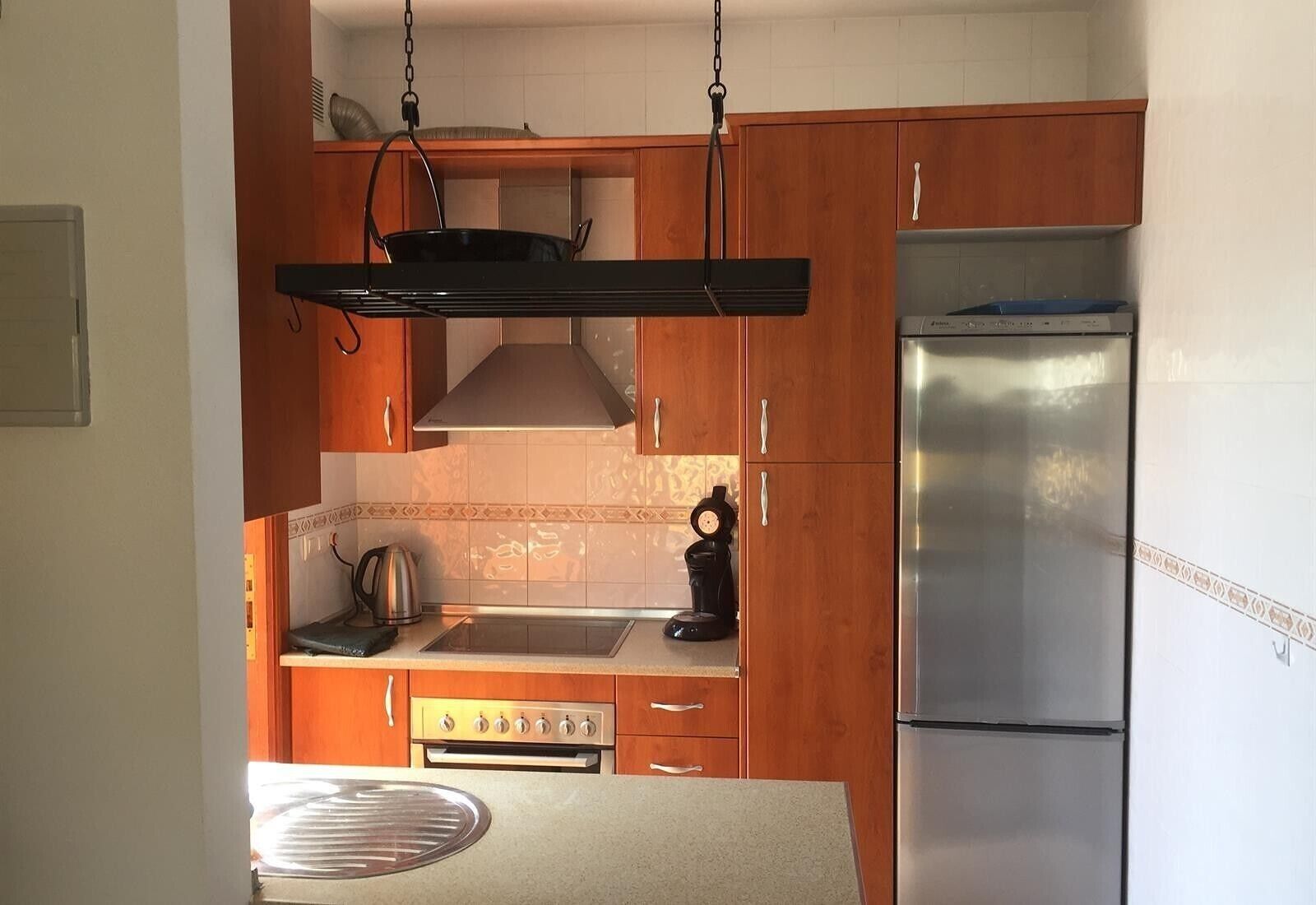 Eine Küche mit Holzausstattung, einem Edelstahlkühlschrank, einem Herd und einem Topfhalter.