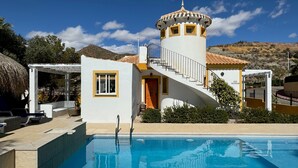 Blick auf einen Pool mit einem Gebäude, das eine Wendeltreppe, einen kleinen Turm und einen Pool zeigt.