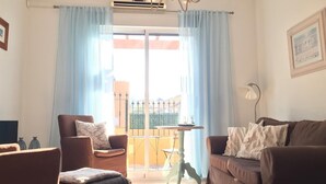 Ein Wohnzimmer mit einer Couch, einem Sessel und einem kleinen Tisch mit Lampe.