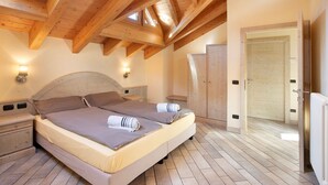 A bedroom with a wooden ceiling, a bed with two pillows, a nightstand, and a door. - 'Appartamento 8' with Mountain View, Shared Garden & Wi-Fi (Livigno)