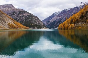 A calm lake with mountains and autumn trees.