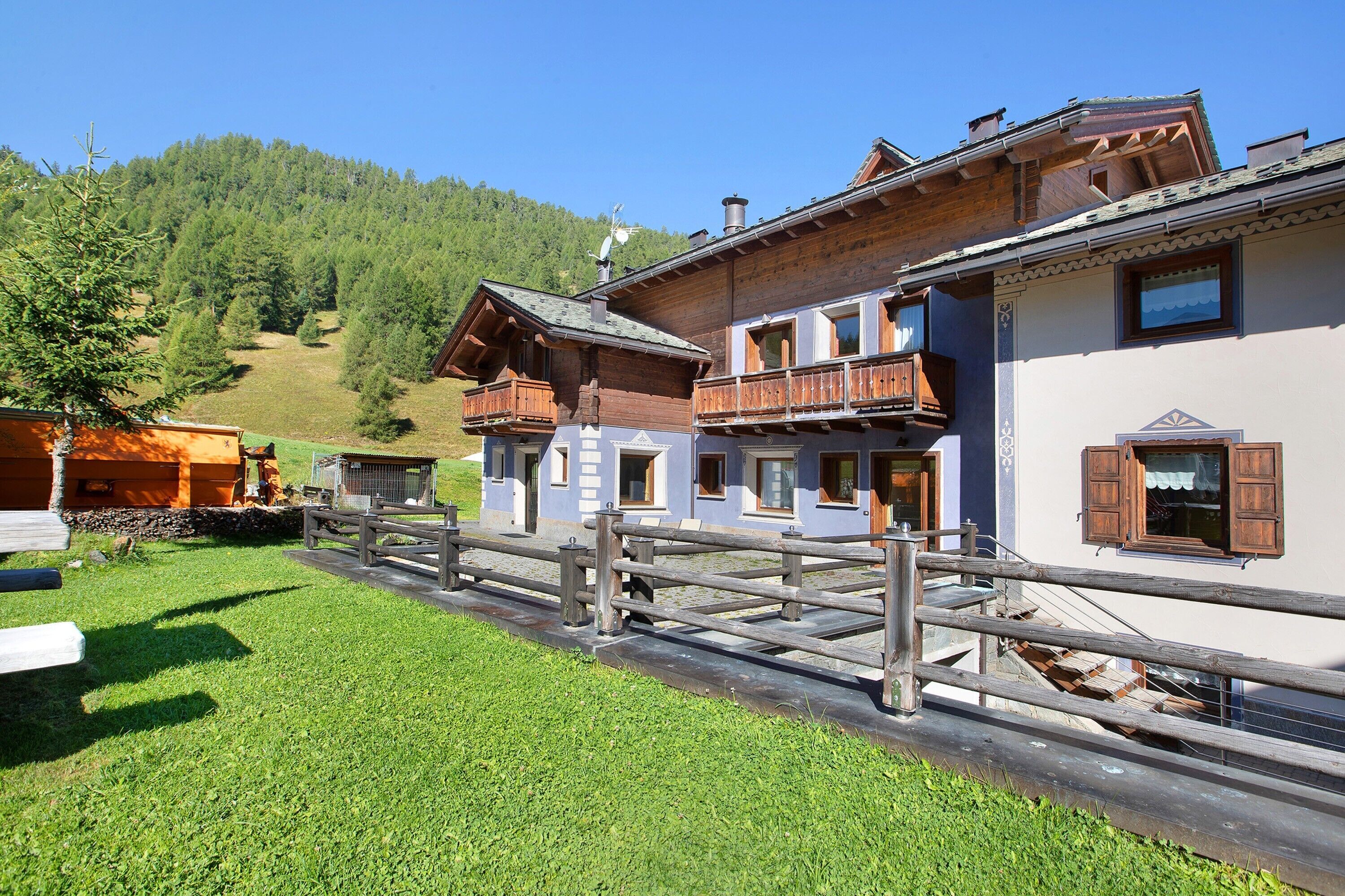 A wooden building with balconies, a wooden fence, and a grassy area.